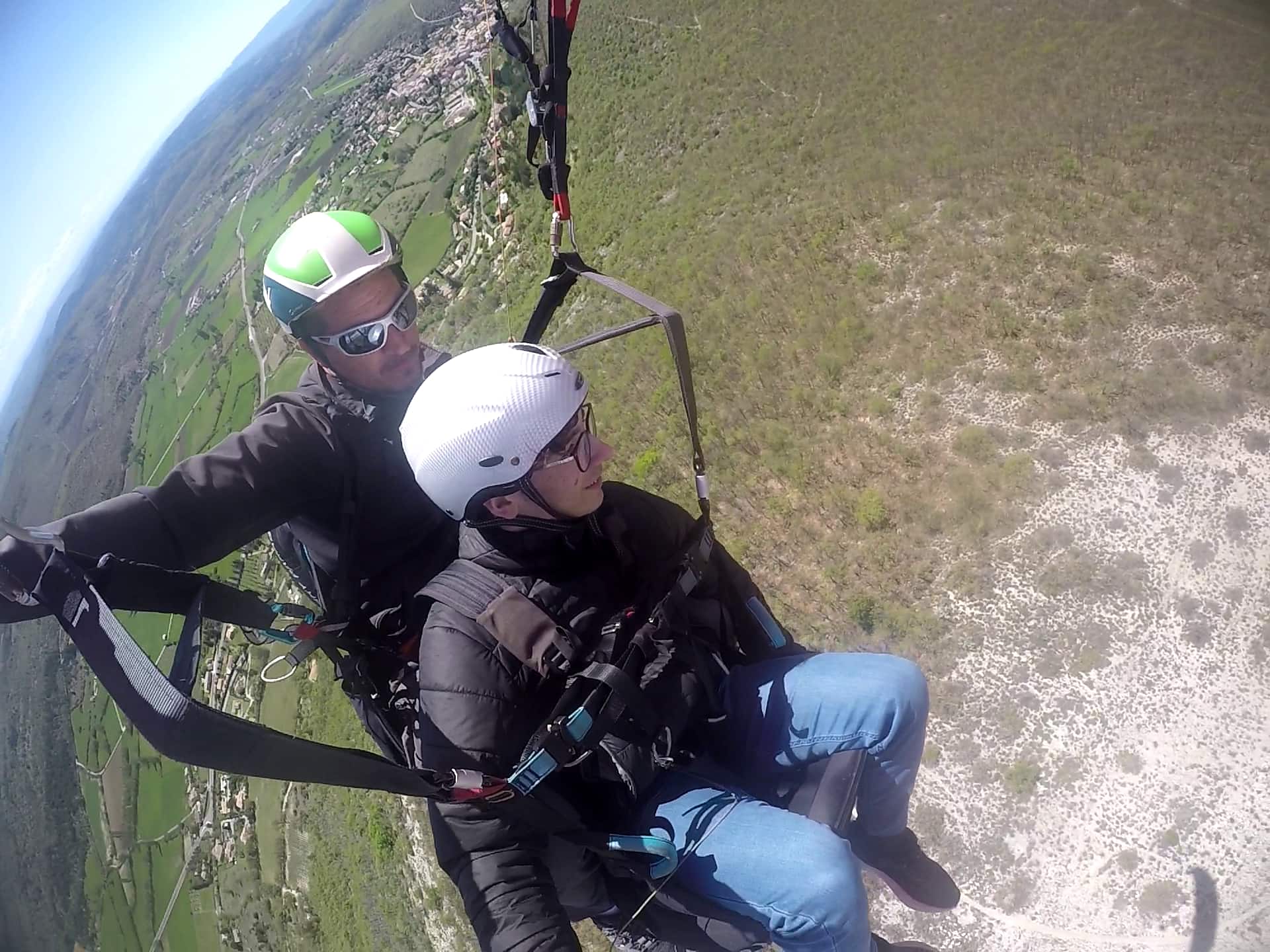 Parapente biplace au-dessus d'un village du Luberon — vue plongeante depuis Banon