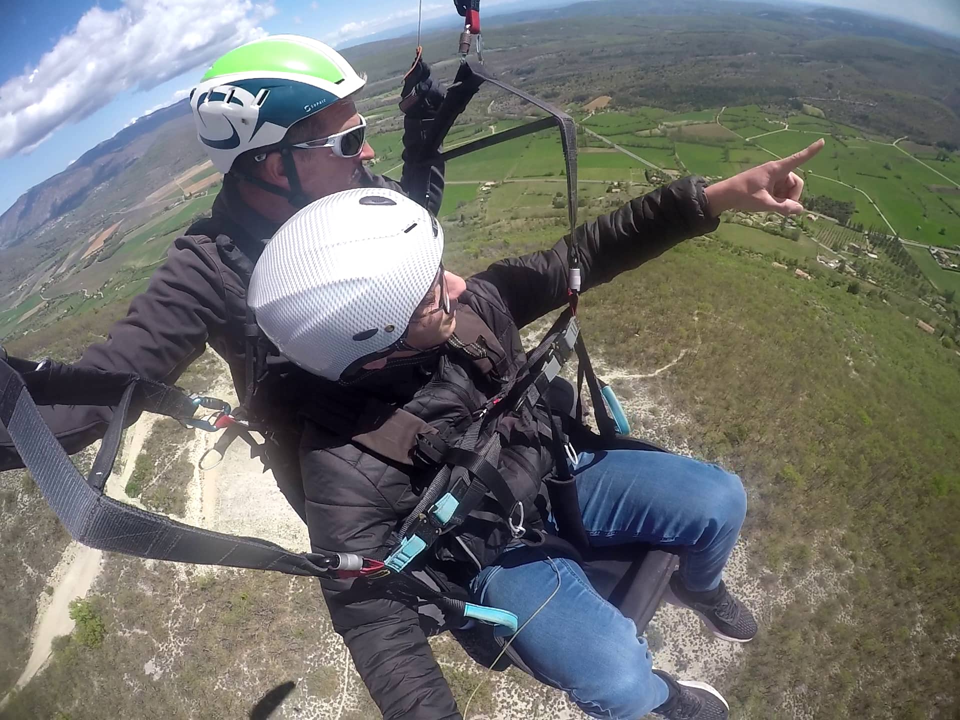 Passager en parapente biplace pointant le paysage de Provence depuis Banon